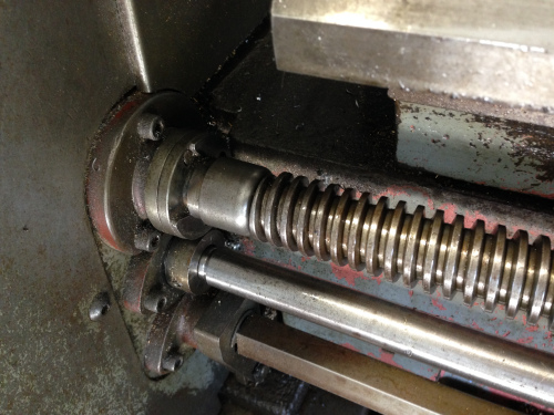 While threading on a lathe, the carriage is moved by means of :